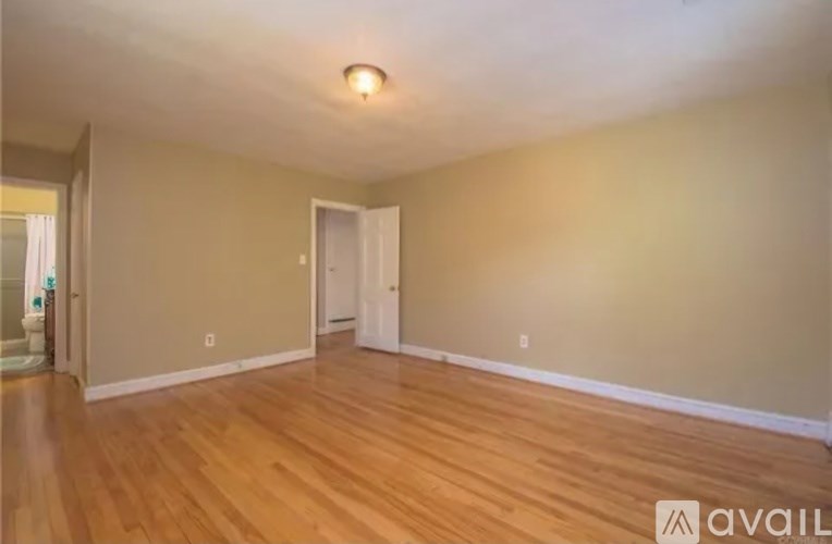 A room with wooden flooring and a door on the right side.
