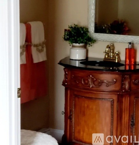 A wooden cabinet with a mirror above it and a potted plant on top.