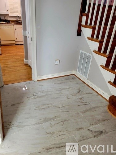 A hallway with a marble floor leading to a staircase.