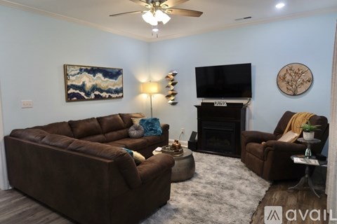 A living room with a brown couch, a fireplace, and a painting on the wall.