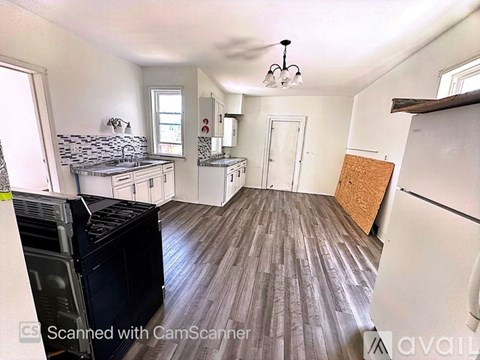A kitchen with a black fridge and wooden floors.