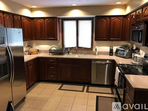 A kitchen with wooden cabinets and a stainless steel refrigerator.