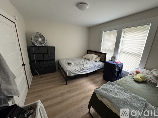 A bedroom with two beds and a fan on the shelf.