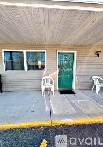 A house with a green door and white chairs outside.
