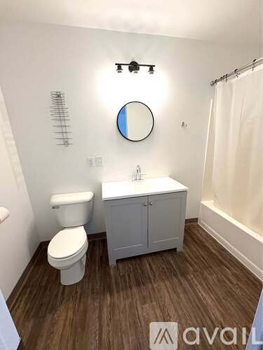 A bathroom with a toilet, sink, and mirror.
