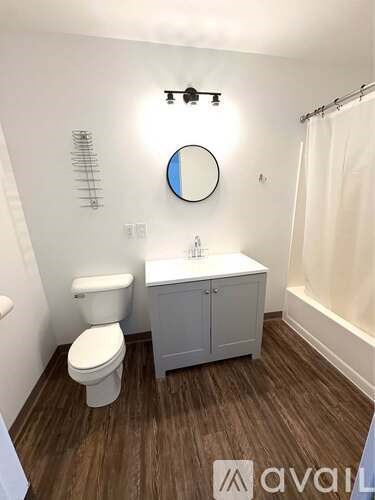 A bathroom with a toilet, sink, and mirror.