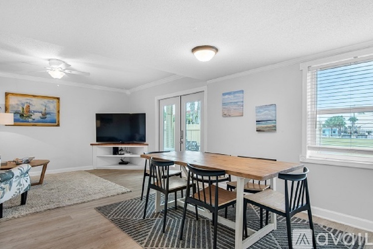 A living room with a television, chairs, and a rug.