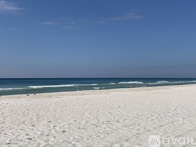 A beach with white sand and a clear blue sky.