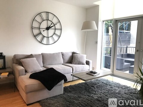 A living room with a grey couch and a black blanket on it.