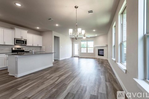 A spacious kitchen with white cabinets and a wooden floor.