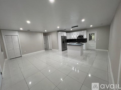 A spacious kitchen and living room with white tiled floors and modern appliances.