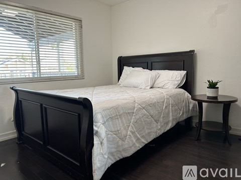 A bedroom with a large bed and a small table with a plant on it.