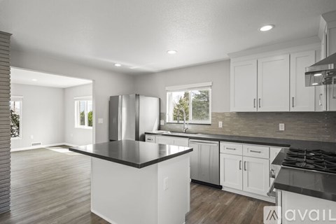 A modern kitchen with white cabinets and a black countertop.
