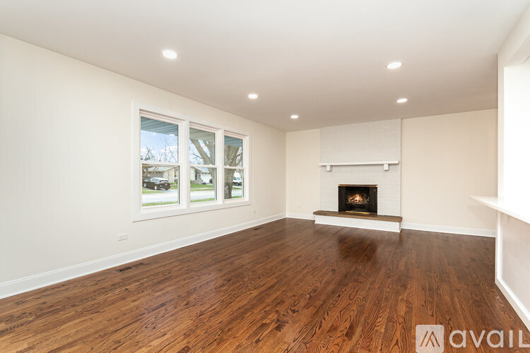 A spacious living room with a fireplace and wood flooring.