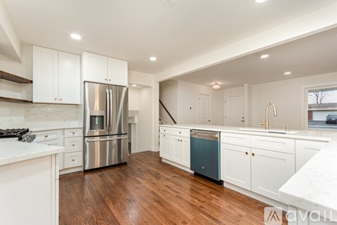 A modern kitchen with white cabinets and a wooden floor.