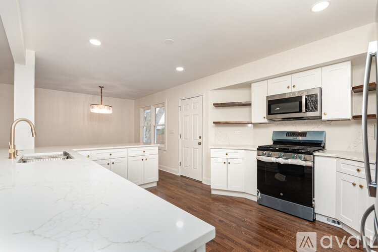 A kitchen with white cabinets and a marble countertop.