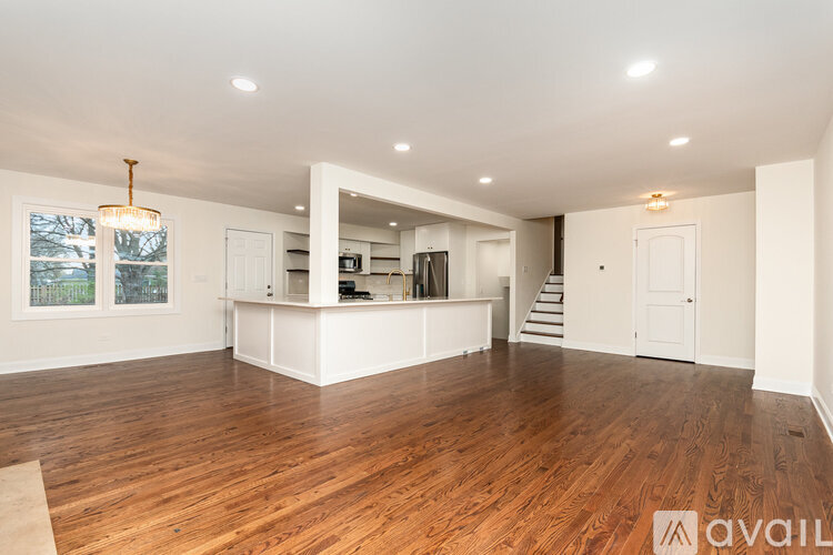 A spacious room with wooden floors and a bar area in the corner.