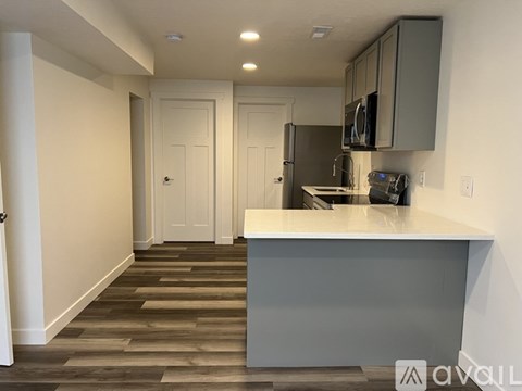 A kitchen with a white counter top and grey cabinets.