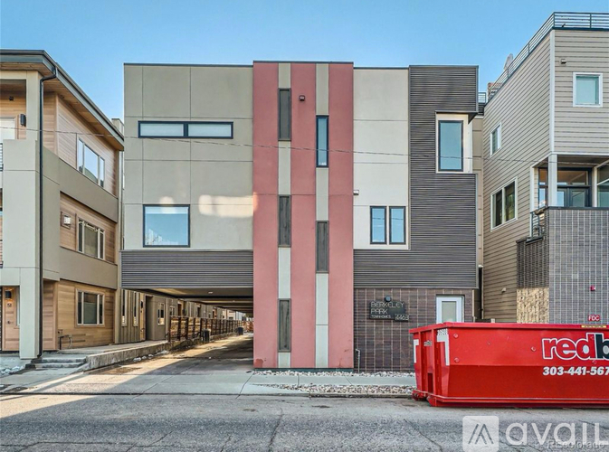 A row of modern townhouses with a red dumpster in front of them.