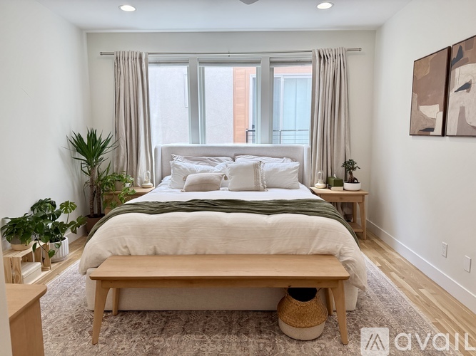 A bedroom with a large bed and a window with curtains.