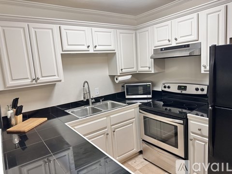 A kitchen with white cabinets and black appliances.