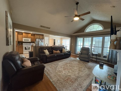 A living room with a black leather couch and a rug.