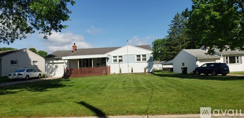 A house with a white exterior and a brown fence is surrounded by green grass.