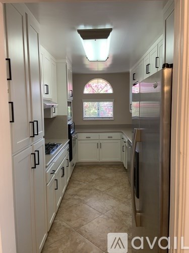 A kitchen with white cabinets and a skylight.