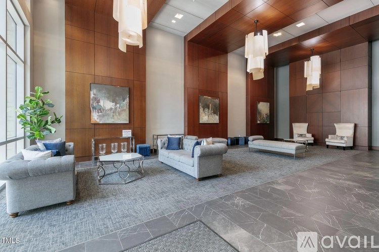 A living room with a grey sofa, a glass coffee table, and a large window.