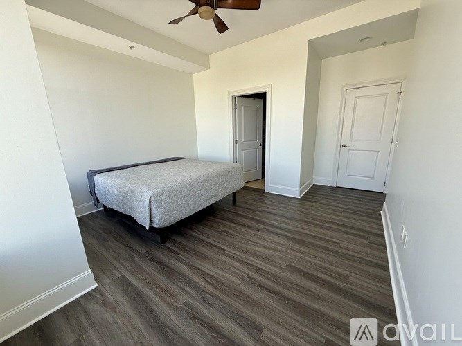A bedroom with a bed, a ceiling fan, and a door.