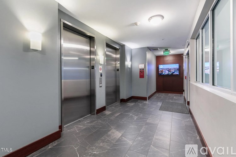 A long hallway with two elevators and a TV mounted on the wall.