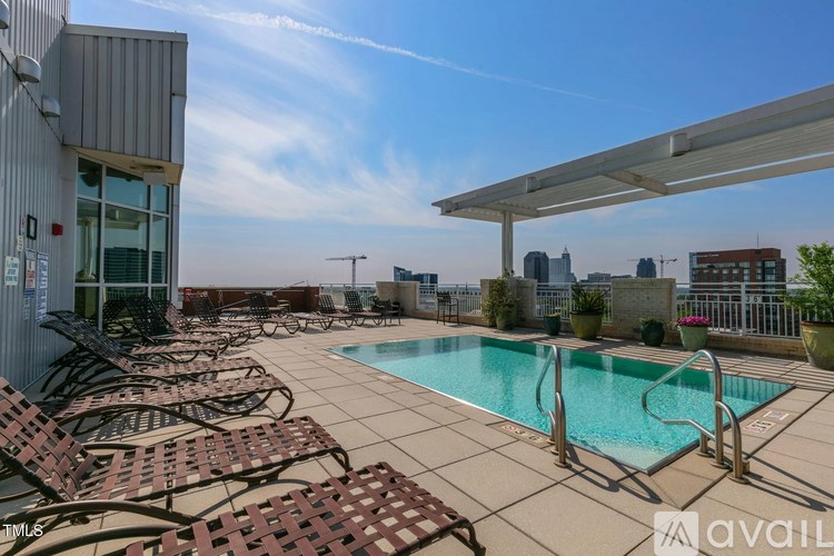 A pool area with sun loungers and a view of the city skyline.