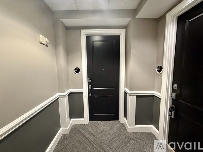 A hallway with a black door and a carpeted floor.