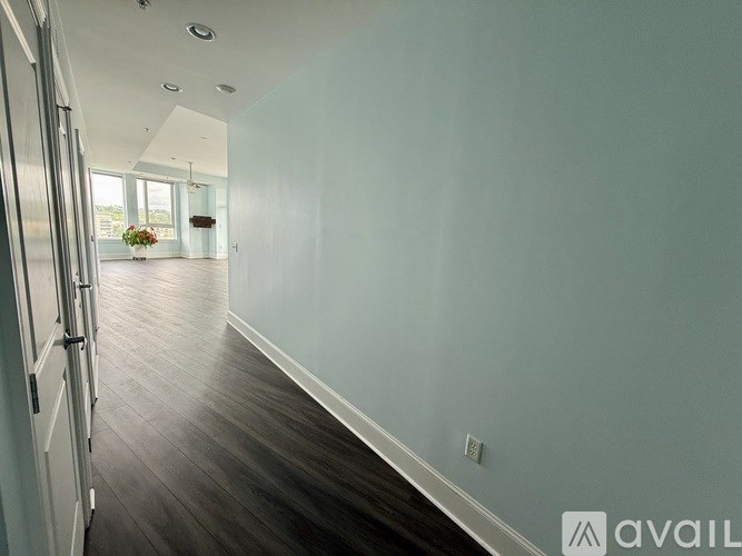 A long hallway with a door on the left and a vase of flowers on the right.