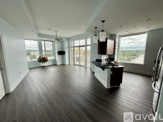 A spacious room with wood flooring and a large window overlooking a cityscape.