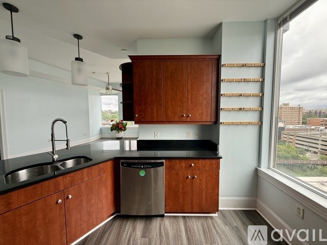 A kitchen with wooden cabinets and a stainless steel trash can.