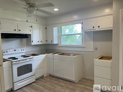 A kitchen with white cabinets and a white stove top oven.