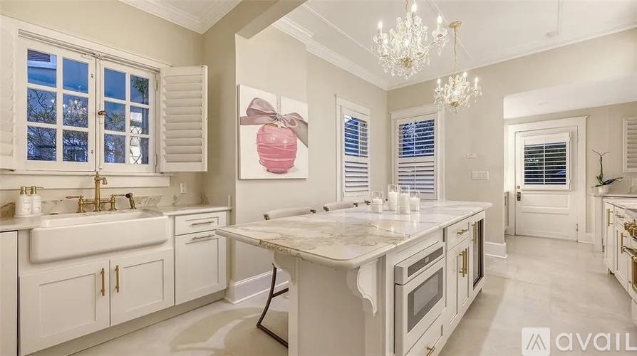 A kitchen with white cabinets and a marble countertop.