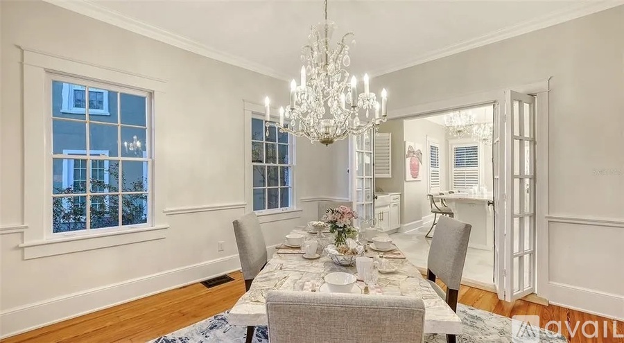 A dining room with a table set for four and a chandelier hanging from the ceiling.