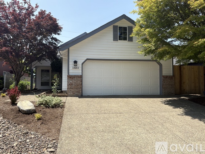 A house with a white garage door and a brown brick wall.