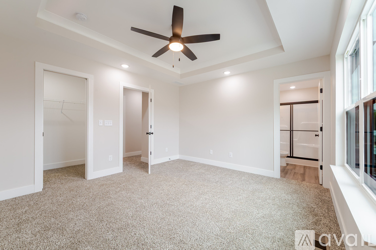 A spacious room with a ceiling fan and carpeted floor.