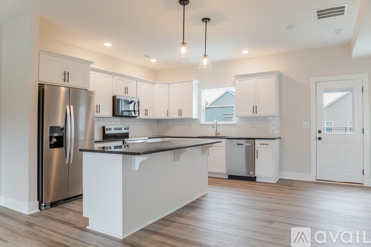 A modern kitchen with a stainless steel refrigerator and white cabinets.