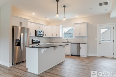 A modern kitchen with a stainless steel refrigerator and white cabinets.