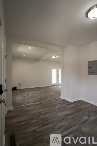 A room with wooden flooring and white walls.