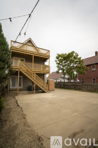 A wooden two-story house with a balcony and stairs leading to the second floor.