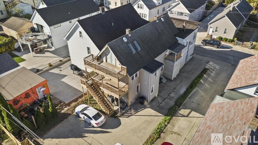 A house with a white exterior and a black roof is surrounded by other houses.