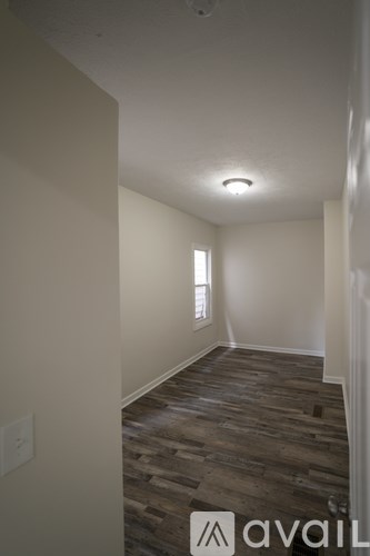 A room with wooden flooring and a window letting in light.