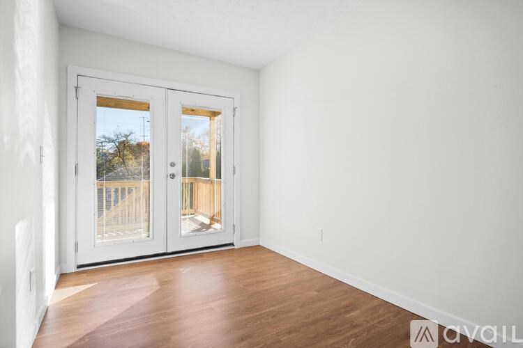 A room with a white wall and a wooden floor with a sliding glass door.