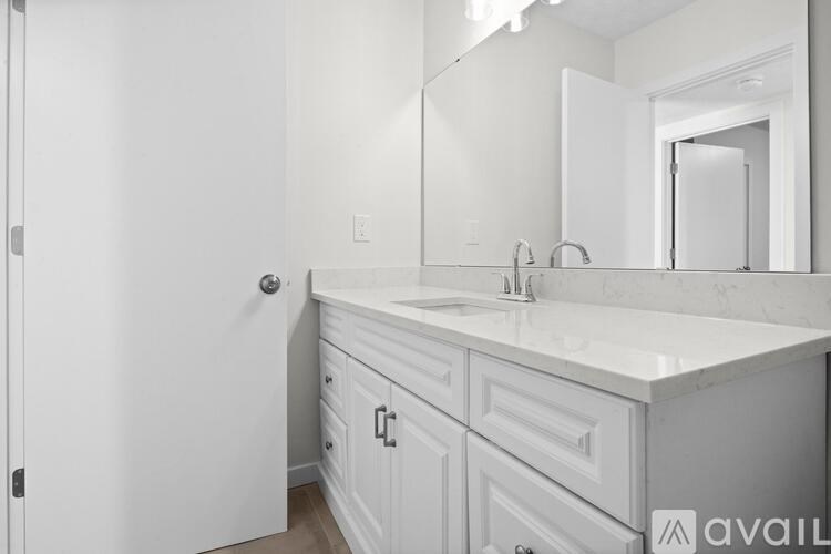 A white bathroom with a sink and mirror.