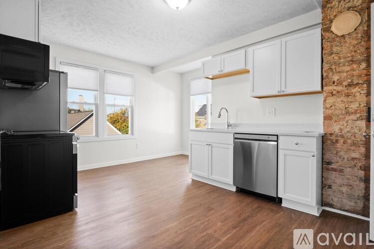 A kitchen with white cabinets and a brick wall.